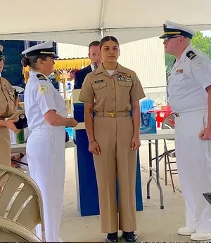U.S. Navy officers in uniform participating in a formal ceremony under a tent.