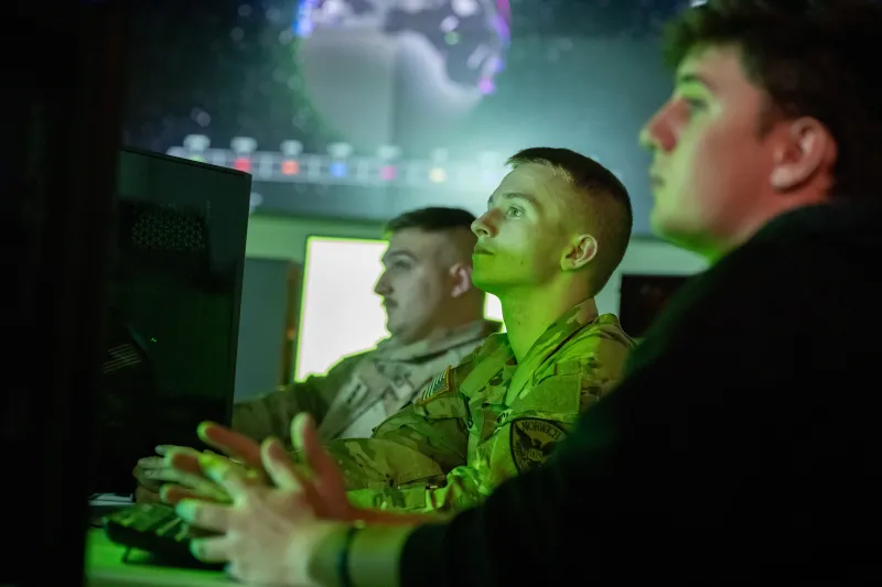 Three students in front of a computer in the Norwich University Cyber War Room.