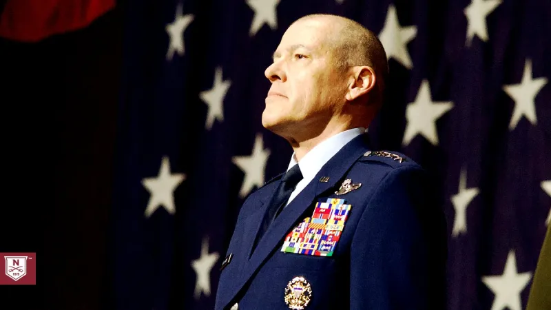 General Bussiere stands at attention in full dress Air Force uniform in front of a large American flag.