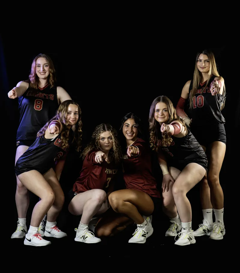 Volleyball players pose against a black background.