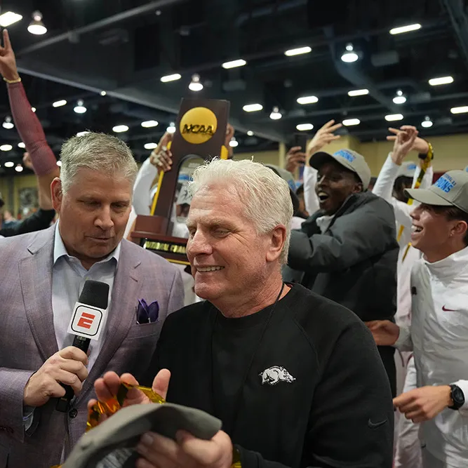 A man celebrates with his team as an ESPN reporter interviews him.