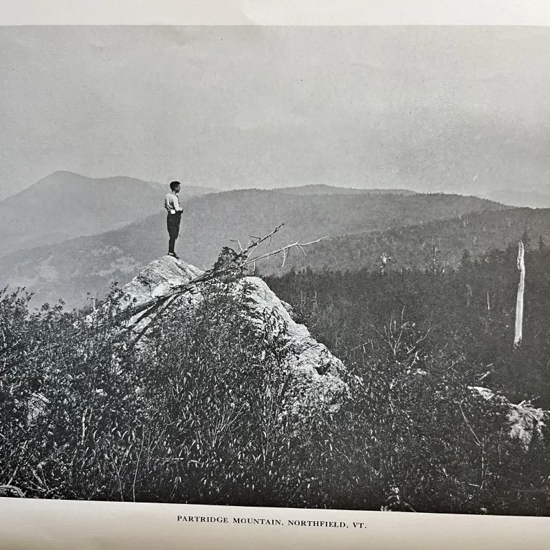 A person stands on a rocky ledge above Partridge Mountain in Northfield, Vermont.