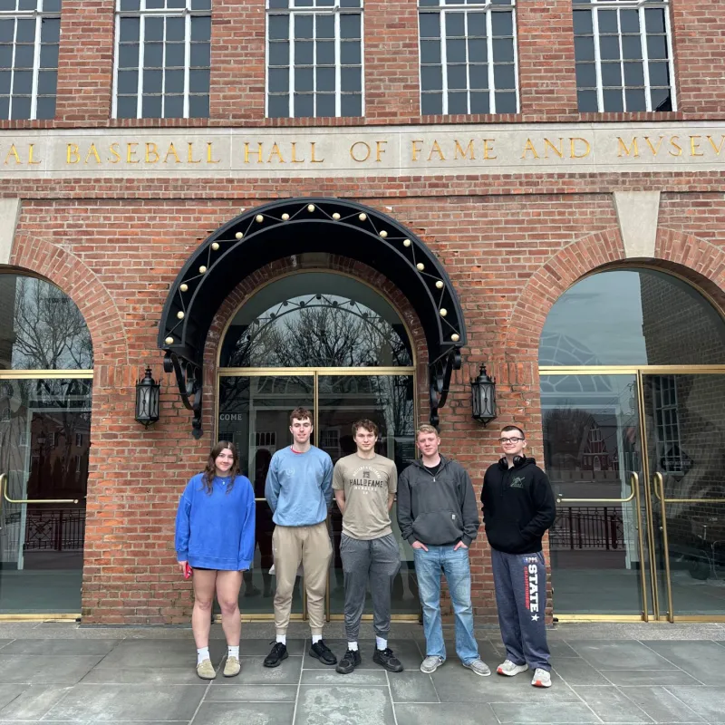 Five students stand outside the National Baseball Hall of Fame and Museum entrance.